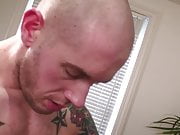 Dude with shaved head is on his knees deep throating hard cock